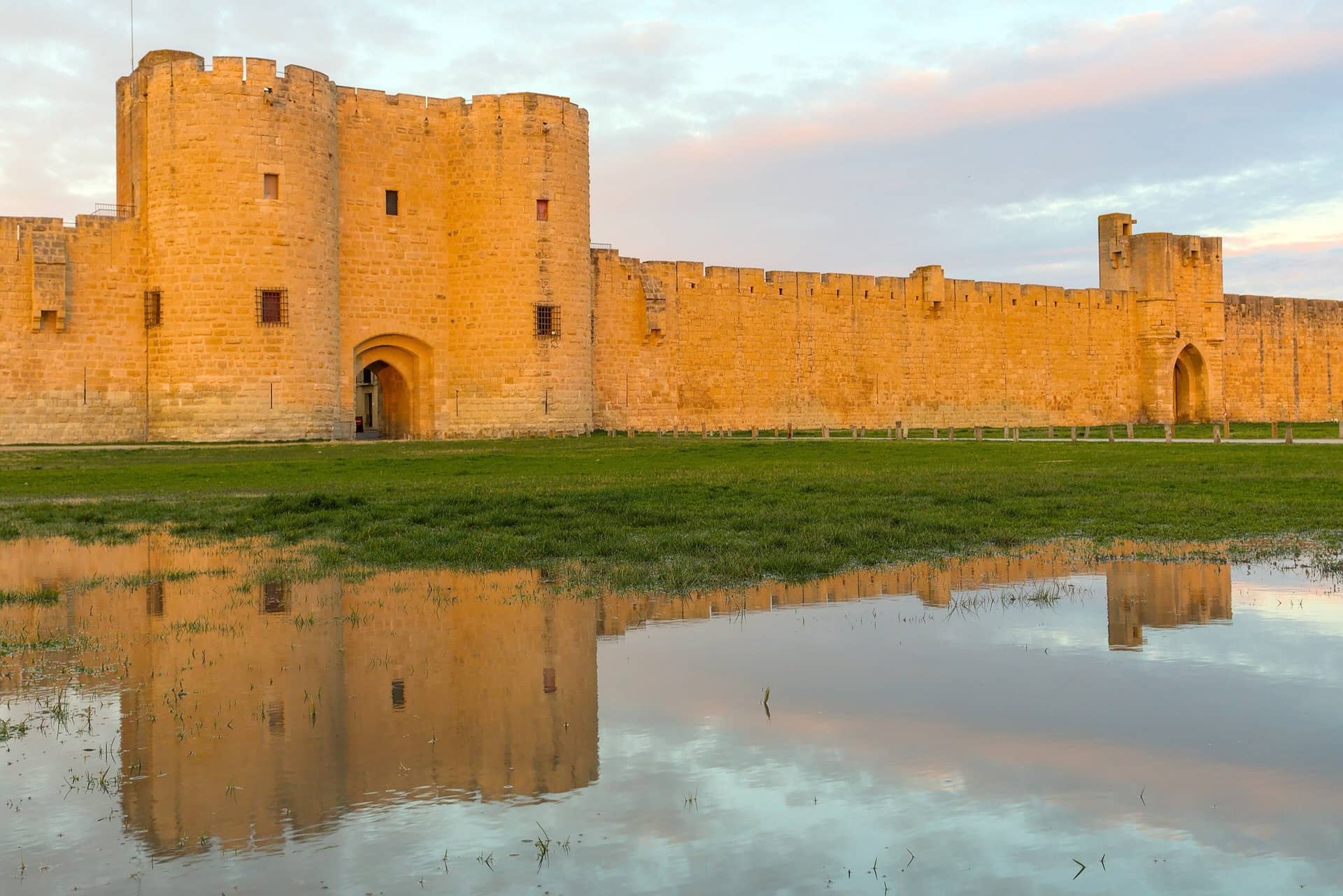 The medieval curtain wall and towers of Aigues-Mortes standing against a low evening sky.