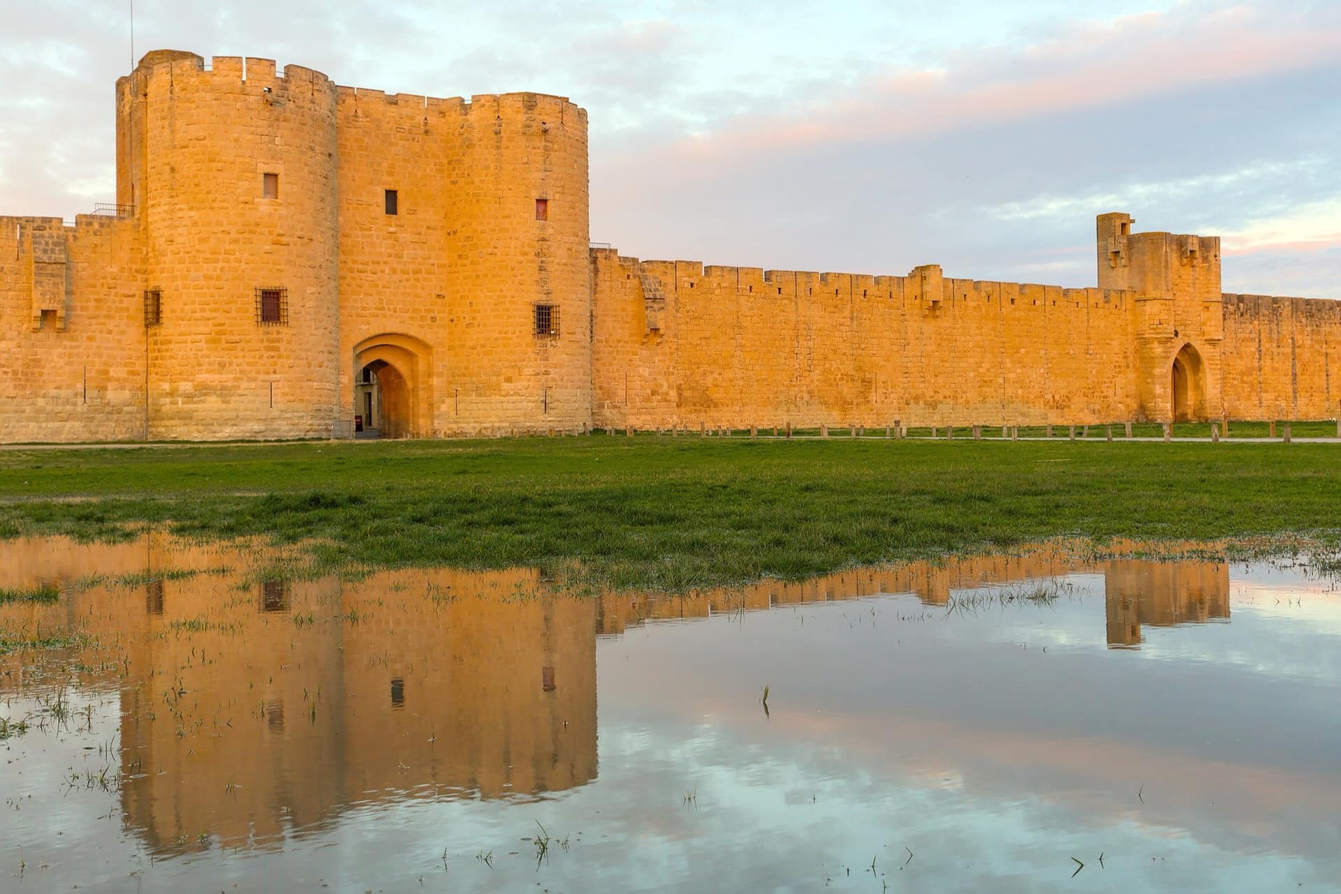 The medieval curtain wall and towers of Aigues-Mortes standing against a low evening sky.