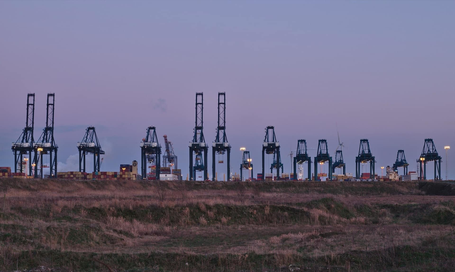 Container cranes at the port of Antwerp lined up against the last light of the day.